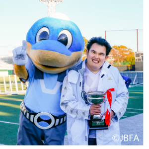 寺西一選手。トロフィーを持ちながら、フロン太くんと笑顔で写っている。